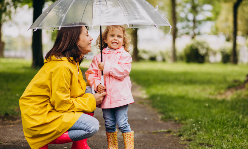 A mother and a child under an umbrella in a park.