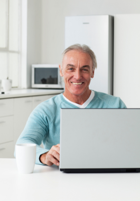 Man sitting in his kitchen, using his laptop.