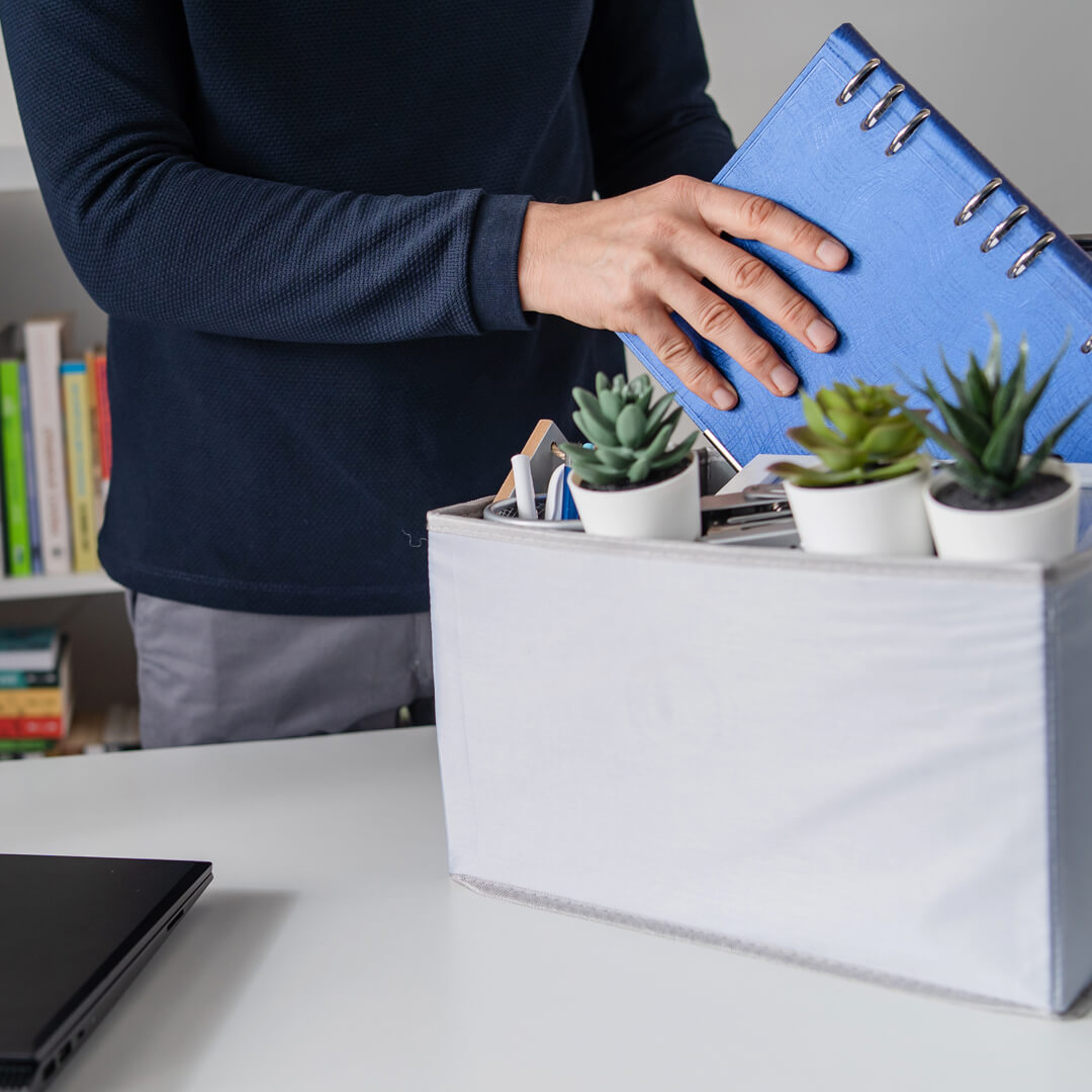 Man cleaning out his desk after a layoff and taking out a notebook to work on his finances.