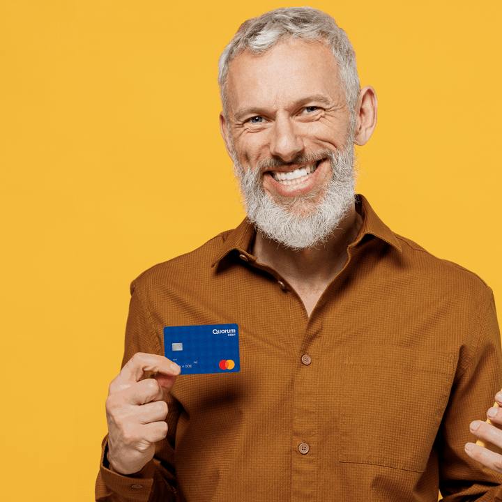 A man in his 60s holding a Quorum Debit Mastercard.
